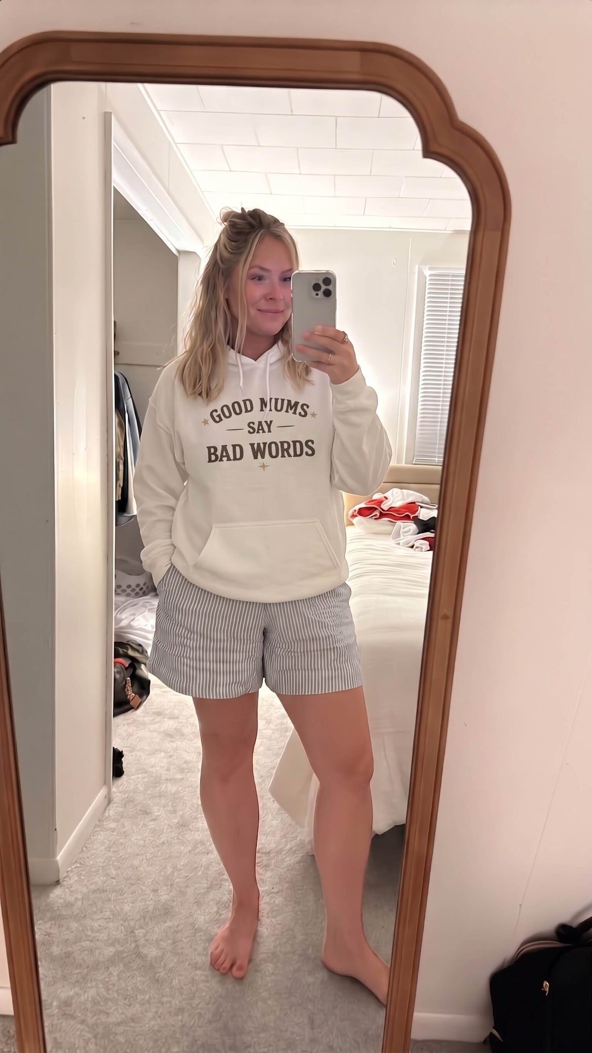 Kiksy white hoodie with Good Mums Say Bad Words printed on the front worn by a smiling woman