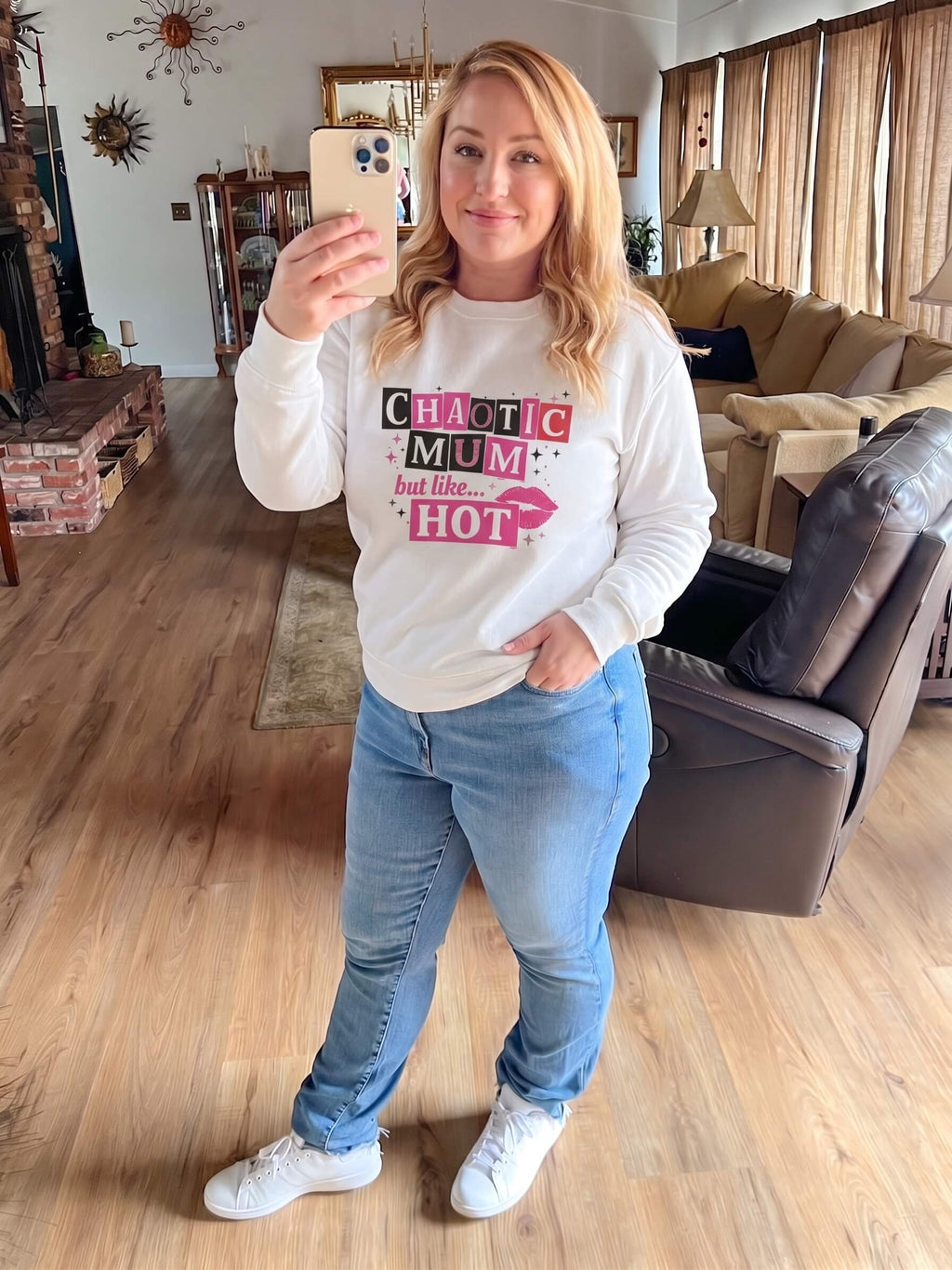 Kiksy white sweatshirt featuring a pink and black Chaotic Mum but like HOT graphic print worn by a smiling woman