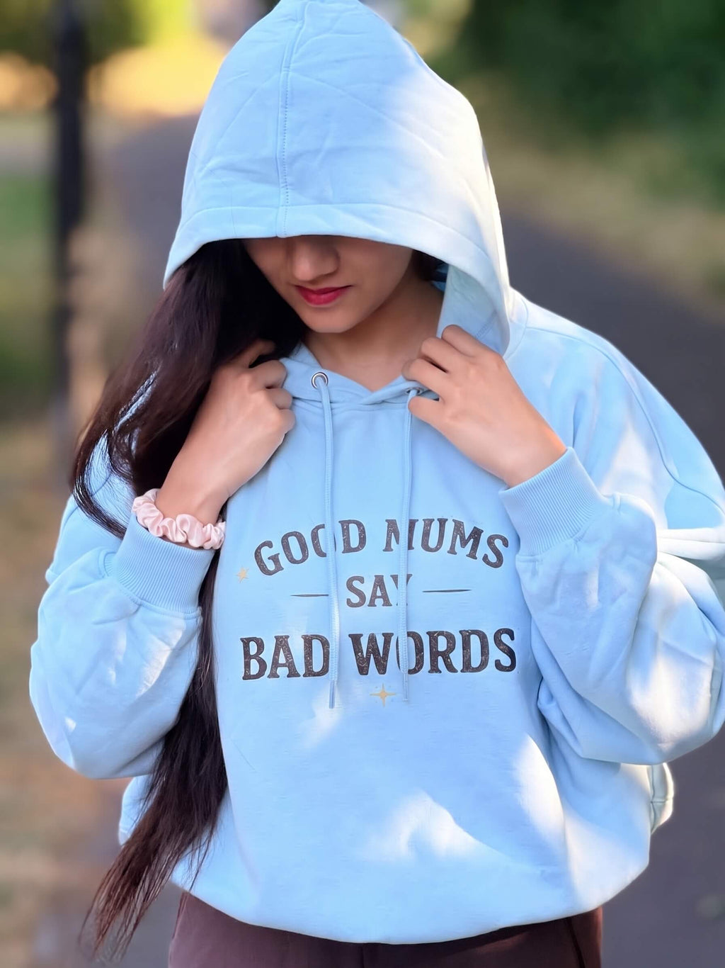 Kiksy sky blue hoodie with Good Mums Say Bad Words printed on the front worn by a smiling woman