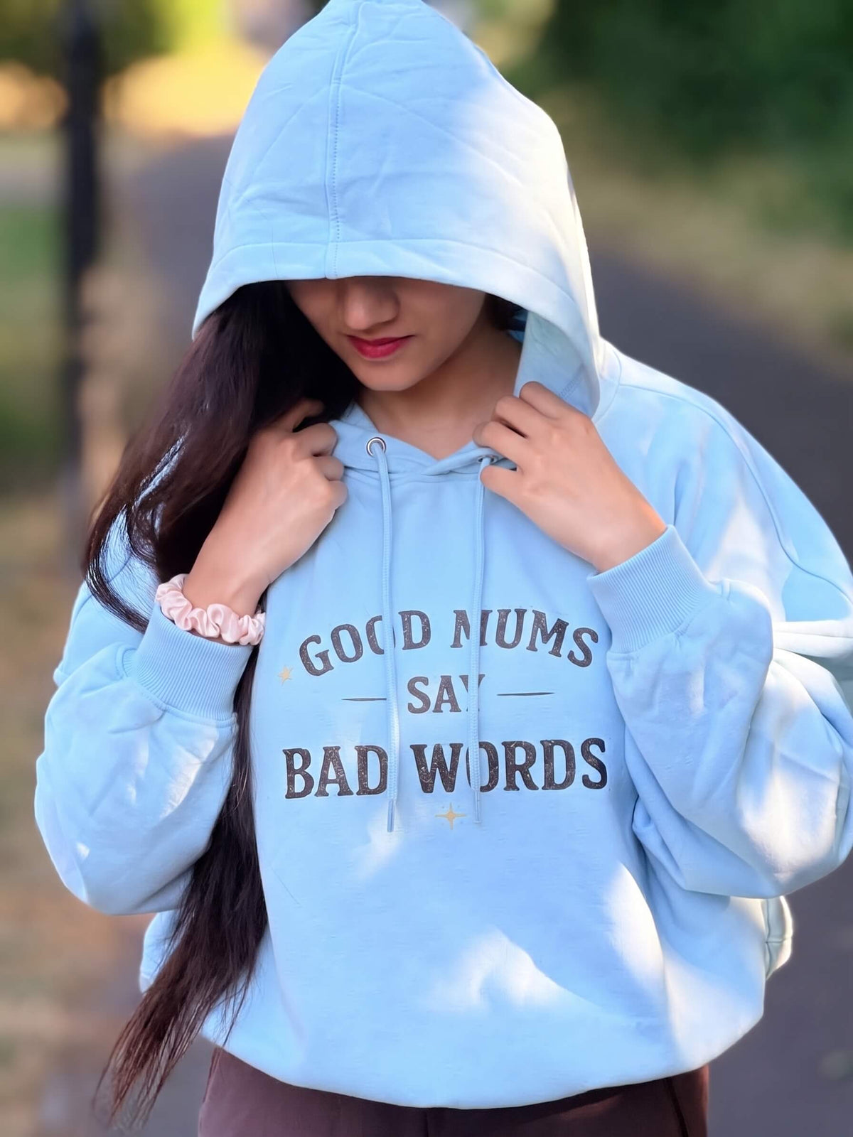 Kiksy sky blue hoodie with Good Mums Say Bad Words printed on the front worn by a smiling woman