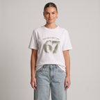 Woman wearing Kiksy white relaxed slogan t-shirt featuring Please Don't Say 67 print with casual blue jeans.