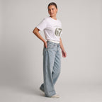 Woman wearing Kiksy white relaxed slogan t-shirt featuring Please Don't Say 67 print with casual blue jeans.