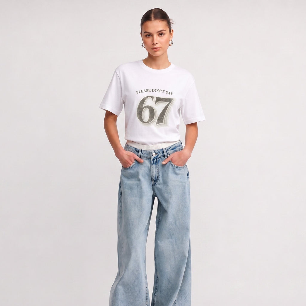 Woman wearing Kiksy white relaxed slogan t-shirt featuring Please Don't Say 67 print with casual blue jeans.