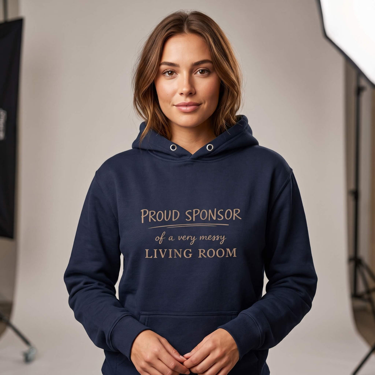 Woman wearing Kiksy dark blue hoodie featuring the text Proud Sponsor of a very messy LIVING ROOM