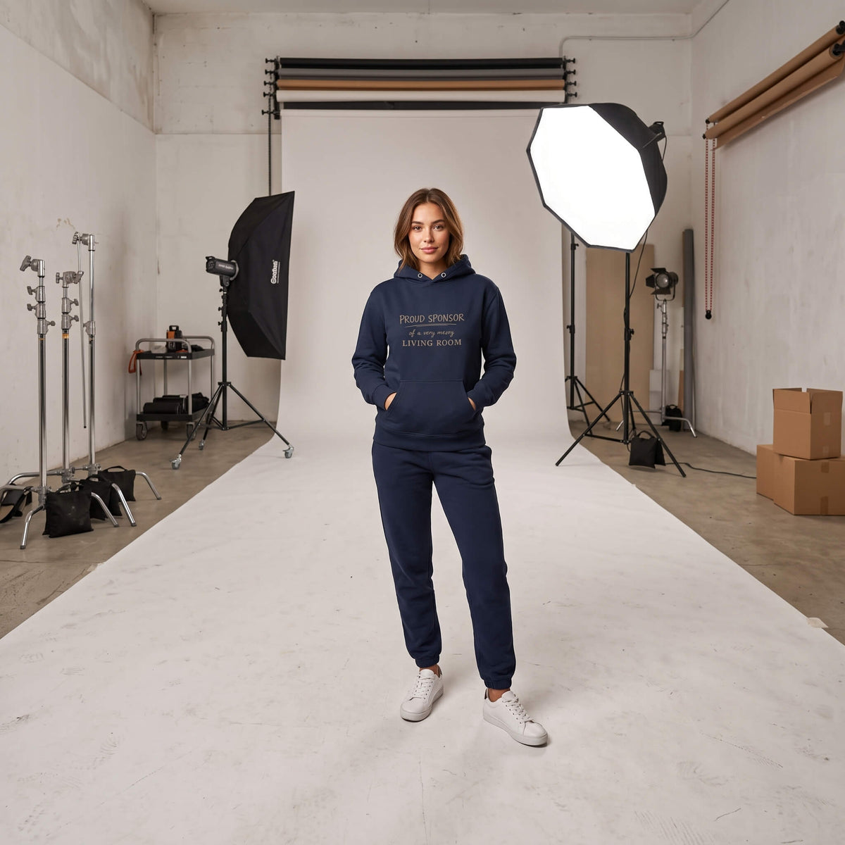 Woman wearing Kiksy dark blue hoodie featuring the text Proud Sponsor of a very messy LIVING ROOM
