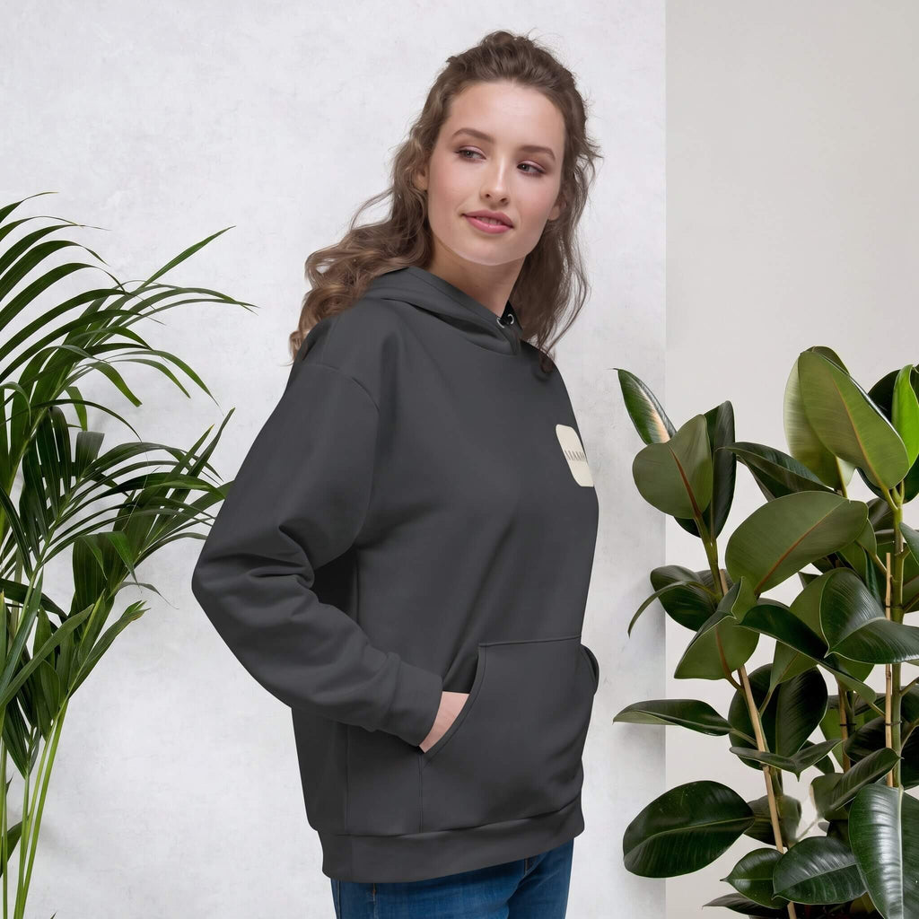 Woman smiling in a Kiksy charcoal grey hoodie featuring a cream square MAMA chest logo.