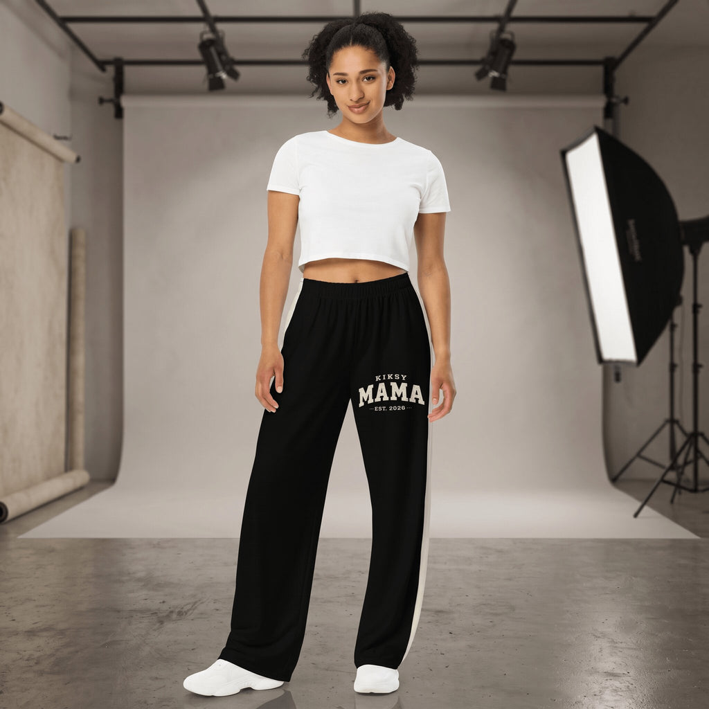 Kiksy black wide leg mama joggers with white side stripes and collegiate print, worn by a smiling model in a studio.